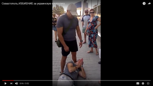 Избитый Мовенко валяется на тротуаре, прося о помощи. Жена предпочитает снимать все на телефон. Ей нужно выставить антироссийкое видео.